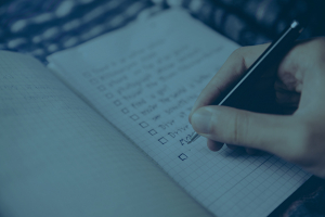 Person writing out checklist in a notebook.