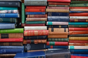 Multicolored vintage books in a jumble on a bookshelf to symbolize the love of languages at academic language conferences.