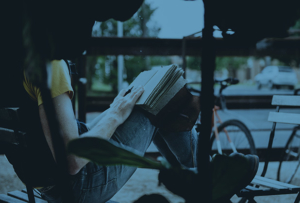 Student reading sitting in a comfortable chair outdoors.